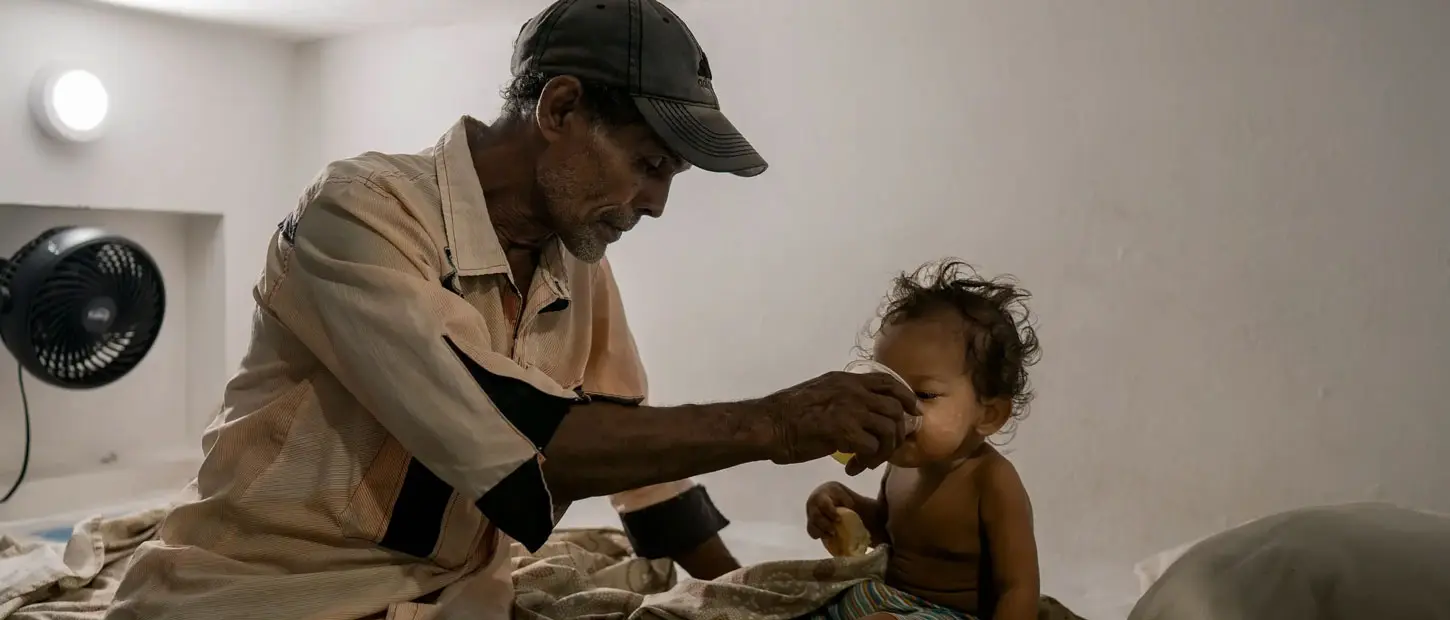 A father gives his child a drink